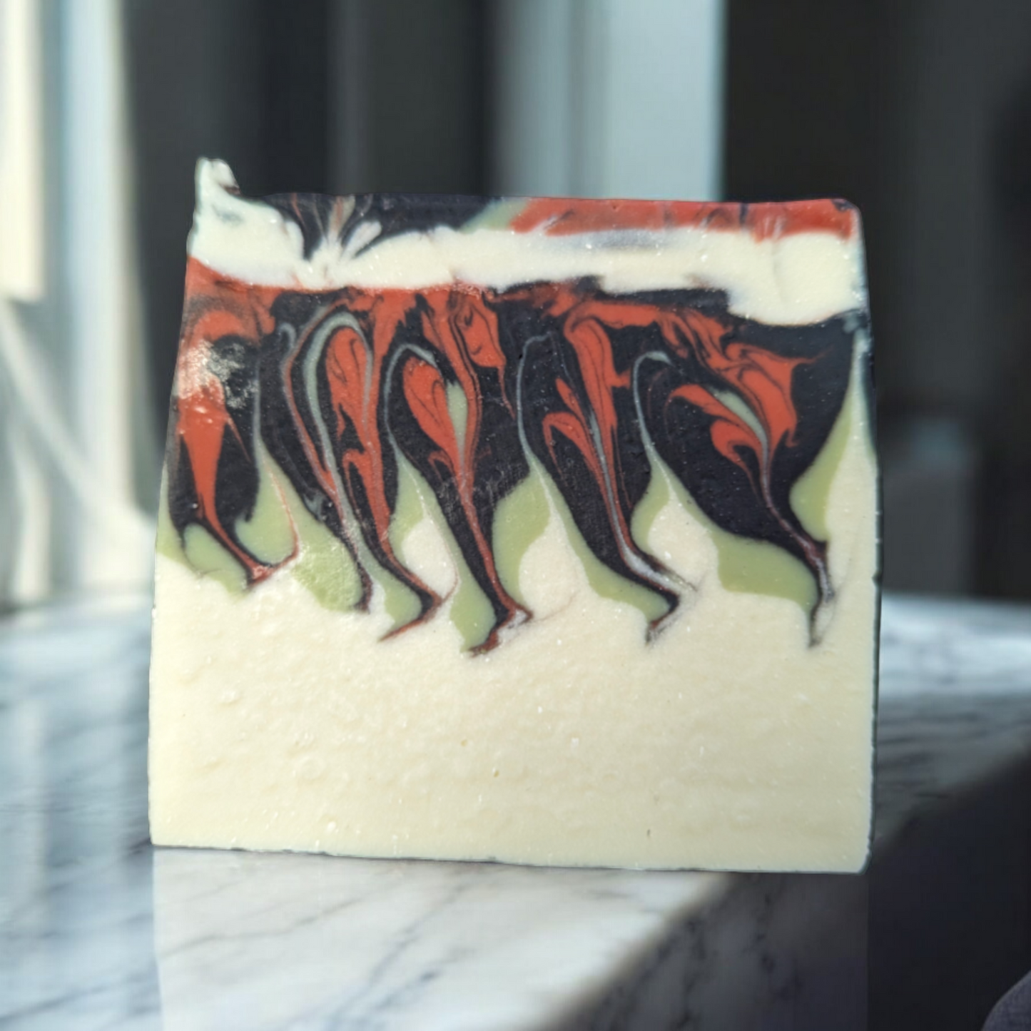 A handcrafted, cold process bar with a naturally textured surface in muted earthy tones, enriched with kaolin, French green, and rose clays along with activated charcoal for gentle, effective cleansing.