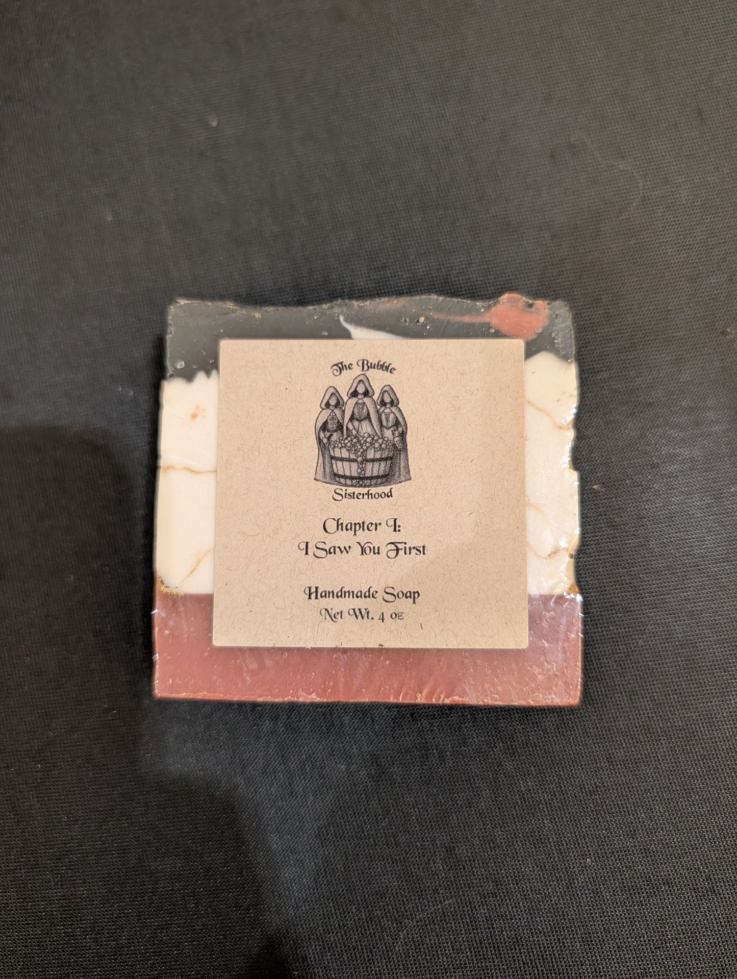 Chapter I: I Saw You First handmade soap with dark burgundy base, white and gold center, and black top — front label view